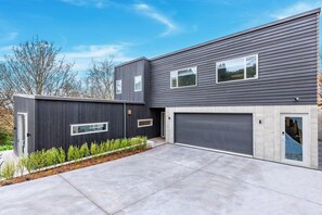 A modern two-story house with a garage, a driveway, and a landscaped front yard.