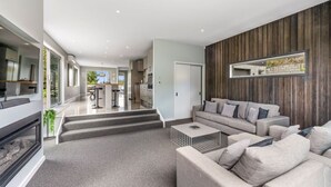 Een moderne woonkamer met een grijze bank, een bijzettafeltje en een houten accentmuur.