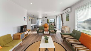 Un salon moderne avec un canapé, des fauteuils, une table basse et un téléviseur.