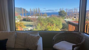 A room with a large window offering a view of a mountainous landscape and a body of water.