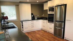 A modern kitchen with white cabinets, a stainless steel refrigerator, and a wooden floor.