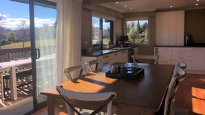 A modern kitchen with a large island, sliding glass doors to a balcony, and a dining area with a view of the outdoors.