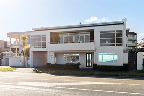 Une maison moderne à deux étages, dotée d’un garage, de grandes fenêtres et d’une pelouse bien entretenue.