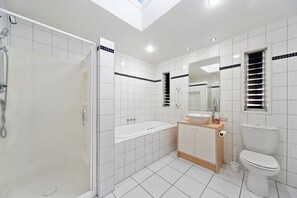 Une salle de bain moderne dotée d’une douche à parois de verre, d’une baignoire sur pieds, d’un meuble-lavabo et de toilettes.