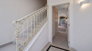 A staircase with ornate white railings leading to a room with a visible door and a light fixture on the wall. - Tui Lookout Hot Tub and Views (Taupo)