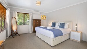 A bedroom with a large bed, bedside tables, a wardrobe, and a window with curtains. - Top of the Lake in Taupo (Taupo)