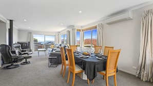 A spacious room with a dining table set for four, a sofa, and a fireplace. - Top of the Lake in Taupo (Taupo)
