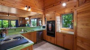 Interior de una cabaña de madera con cocina, que incluye estufa, fregadero y horno.