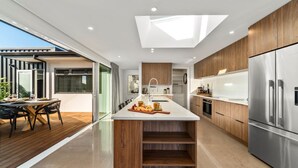 A modern kitchen with a central island, wooden cabinets, stainless steel appliances, and a skylight. - Nga Roto Retreat with Hot Tub (Taupo)