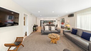 Ein modernes Wohnzimmer mit einem grauen Sofa, einem Holztisch und einem an der Wand befestigten Fernseher.
