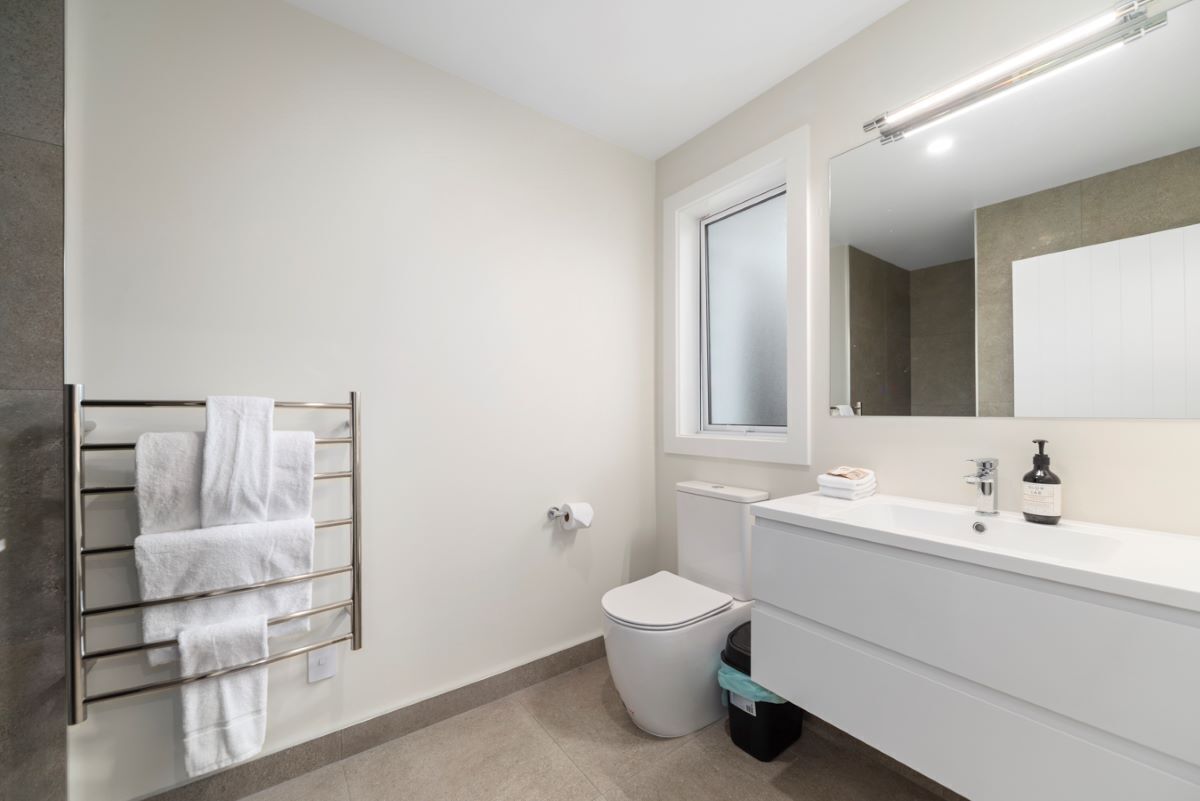 A modern bathroom with a toilet, sink, and towel rack.