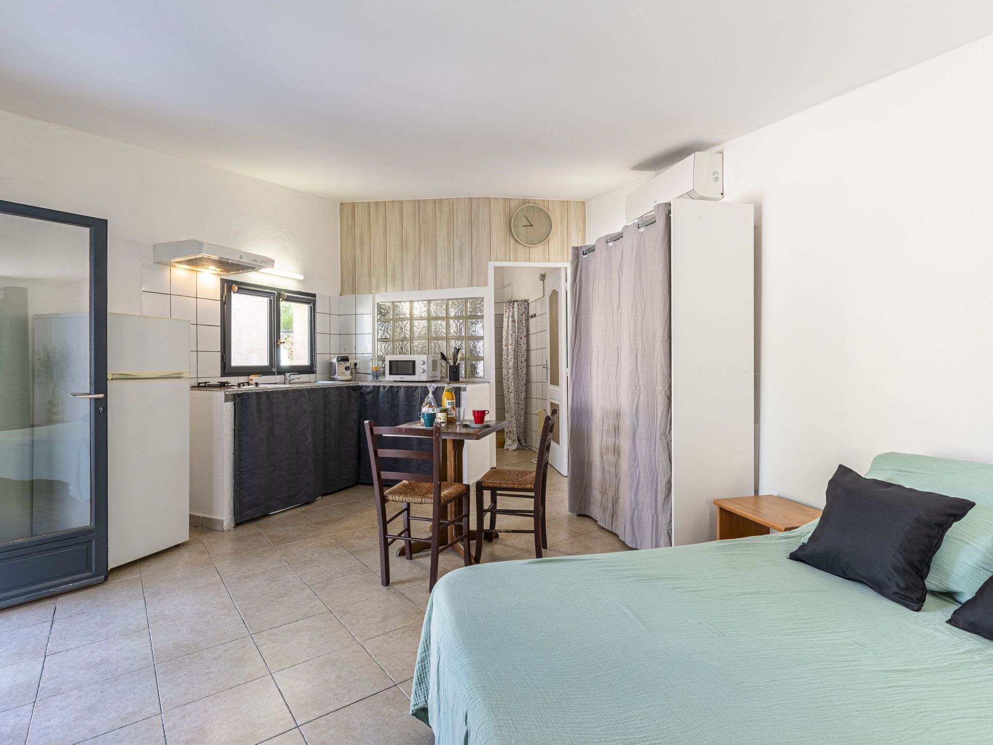 Une petite chambre comprenant un lit, une petite table et un coin cuisine.