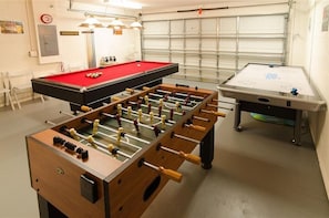 Une pièce équipée d’un baby-foot, d’une table de billard et d’une table de ping-pong.