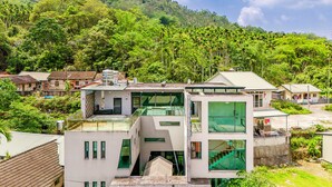 A modern multi-story building with a glass facade, surrounded by lush greenery and hills in the background. - Han Yan Hill Hotel (Yuchi)
