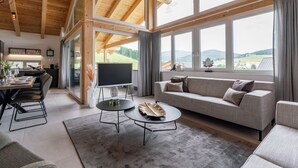 A spacious living room with a large window, a flat-screen TV, and a cozy sofa.