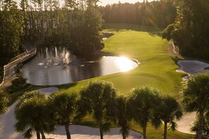 Ein Golfplatz mit Sandbunkern, Wasserhindernissen und Palmen.
