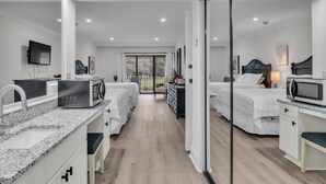 Moderni hotellihuone, jossa on keittotila, parveke, jolta on näkymä, ja erillinen makuuhuone.