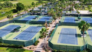 Ilmakuva tenniskeskuksesta, jossa on useita kenttiä, ja jonka ympärillä on palmuja ja muuta vehreää kasvillisuutta.