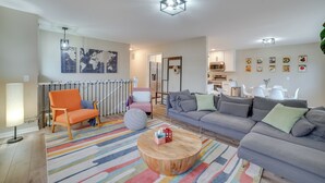 Ein modernes Wohnzimmer mit einer Couch, Sesseln, einem Couchtisch und einem Essbereich mit Stühlen und Tisch.