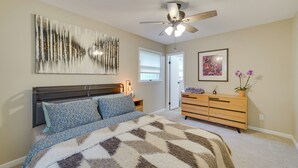 Ein Schlafzimmer mit Bett, Deckenventilator, Kommode und einem Gemälde an der Wand.