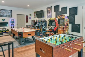 Una habitación con mesa de fútbol de mesa, mesa de billar y juegos de arcade.