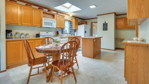 Una cocina con armarios de madera, una isla central y una mesa de comedor con sillas.
