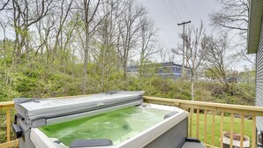 Un jacuzzi en una terraza de madera con vistas a árboles y un edificio al fondo.