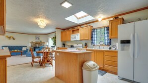 Una cocina compacta con armarios de madera, una isla central, un refrigerador blanco y un tragaluz.