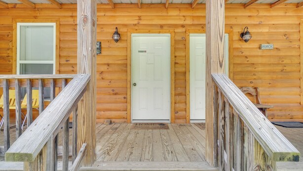 Eine Holzhütte mit Veranda, einer Tür und zwei Laternen.