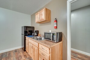 A kitchen with wooden cabinets, a microwave, a sink, and a fire extinguisher. - ATV-Friendly Briceville Studio Near Frozen Head! (Briceville)