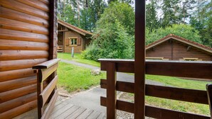 A wooden cabin with a porch, surrounded by a forest. - Apartment 'Blockhaus Hedwig Zwei' with Shared Pool, Private Terrace and Wi-Fi (Stamsried)