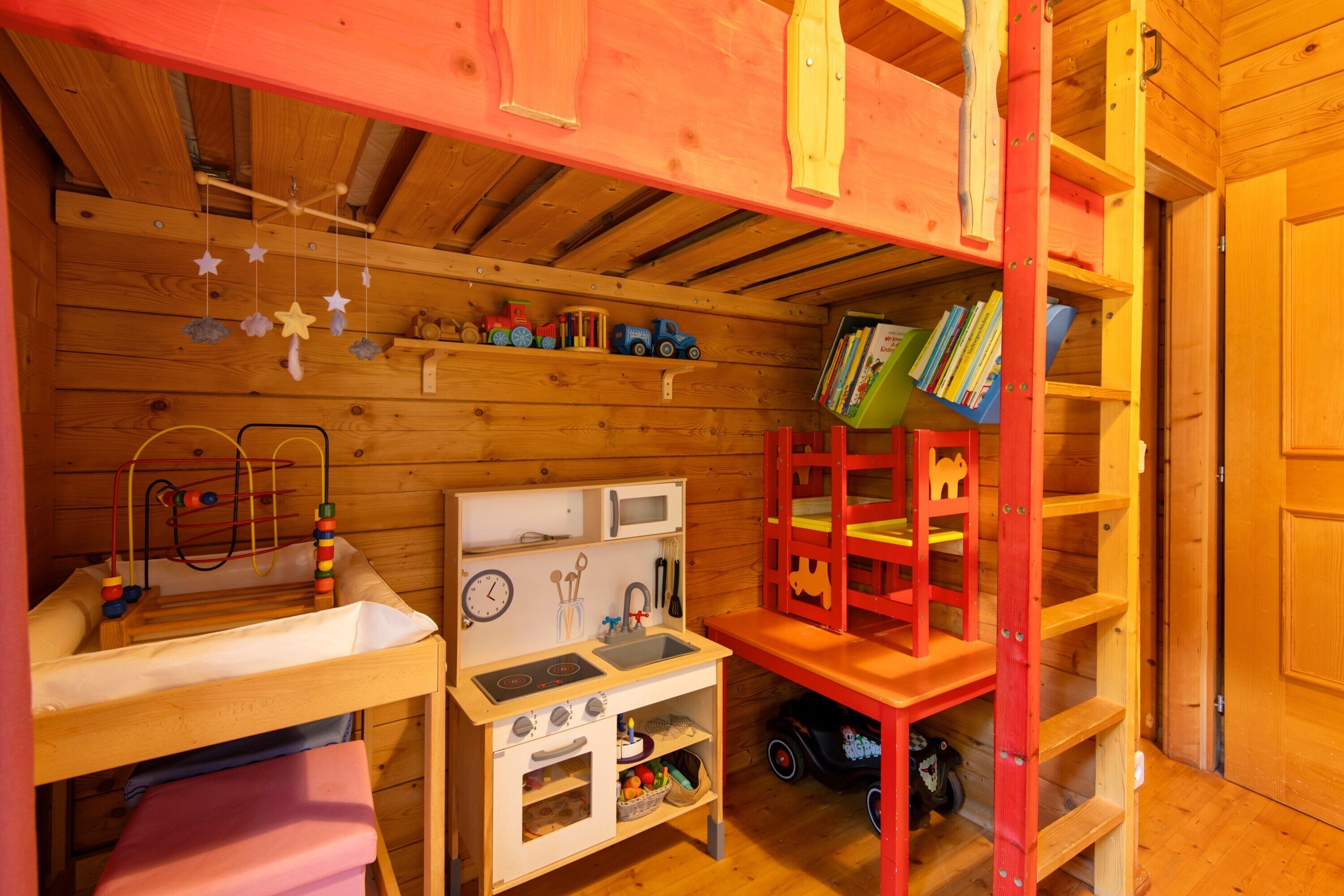 Una habitación acogedora de madera con una cocina de juguete, una estantería y un tren de juguete.