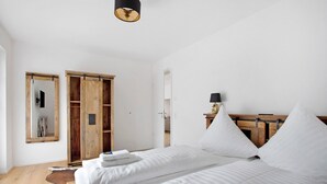 A bedroom with two beds, a wooden wardrobe, a mirror, and a lamp.