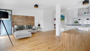A modern living room with a sofa, a wooden dining table, and a kitchen area with white cabinets.
