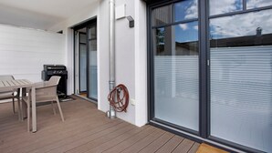 A patio with a table and chairs, a grill, and a hose.
