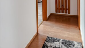 Un couloir avec un plancher en bois, un miroir, un tableau, une porte en bois et un luminaire suspendu.