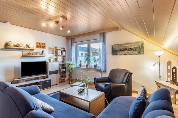 A living room with a TV, sofas, a coffee table, and a bookshelf.