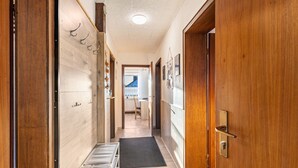 Un pasillo con paredes de madera, una puerta con cerradura y un felpudo negro en el suelo.