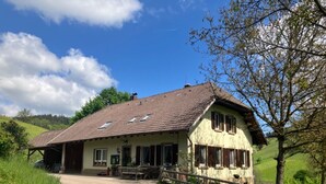 Een traditioneel huis met schuin dak, een voortuin en een pad naar de ingang.