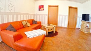 Una sala de estar con un sofá, una mesa de centro, un televisor y una puerta.