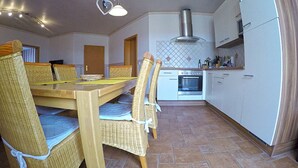 Cocina compacta con comedor, que incluye una mesa, sillas y electrodomésticos básicos.