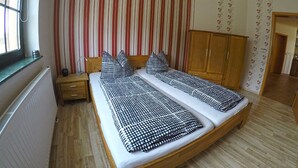 Un dormitorio con una cama litera, cortinas a rayas, un armario de madera y un radiador.