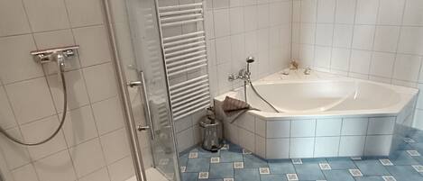 A modern bathroom with a glass shower enclosure, a freestanding bathtub, and a tiled floor with a geometric pattern.