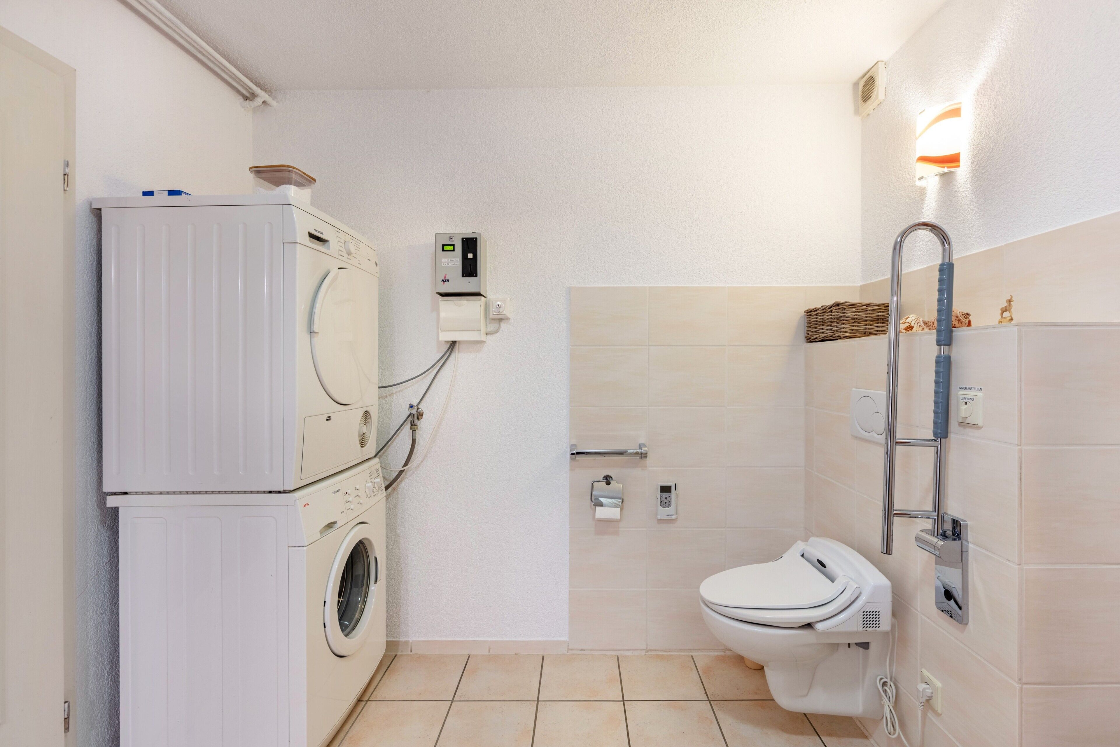 Un bagno compatto con lavatrice, WC e asciugatore a mano.
