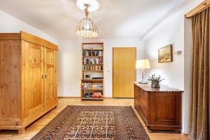A room with a wooden wardrobe, a bookshelf, a desk with a lamp, and a patterned rug. - Holiday Apartment 'Kammbühlhof' with Sauna, Mountain View, Private Terrace & Wi-Fi (Sankt Blasien)