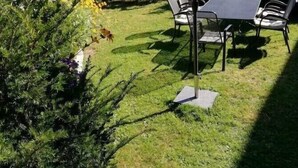 Un patio con una mesa y sillas, un paraguas rojo y vistas a un paisaje montañoso.