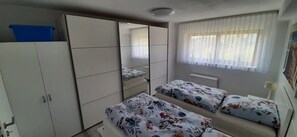 Un dormitorio con dos camas, un armario y una ventana con cortinas.