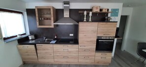 Une cuisine compacte équipée d’une cuisinière intégrée, d’un évier et d’un meuble en bois doté de tiroirs.