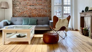 A living room with a brick wall, a sofa, a coffee table, a chair, and a fireplace. - Holiday Home 'Ferienhaus bei Juste' with Private Terrace, Shared Garden and Wi-Fi (Schotten)