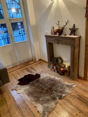 Une pièce avec une cheminée, un tapis en fourrure et une décoration en forme d’étoile au mur.